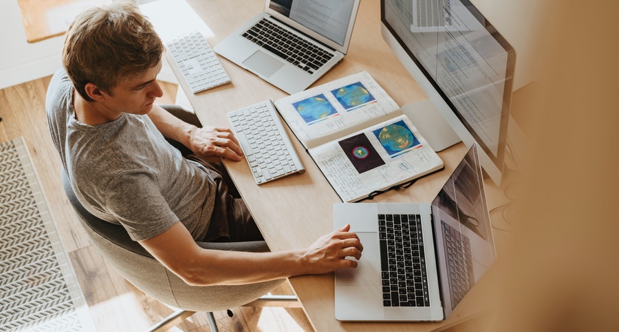 man working from home with three computers