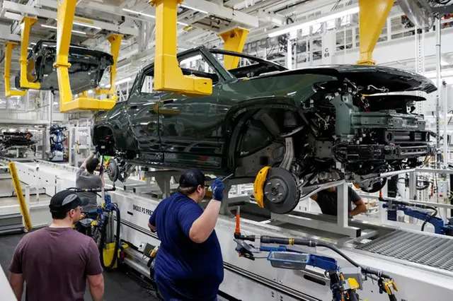 Employees work on an assembly line at startup Rivian Automotive's electric vehicle factory in Normal, Illinois, U.S. April 11, 2022.