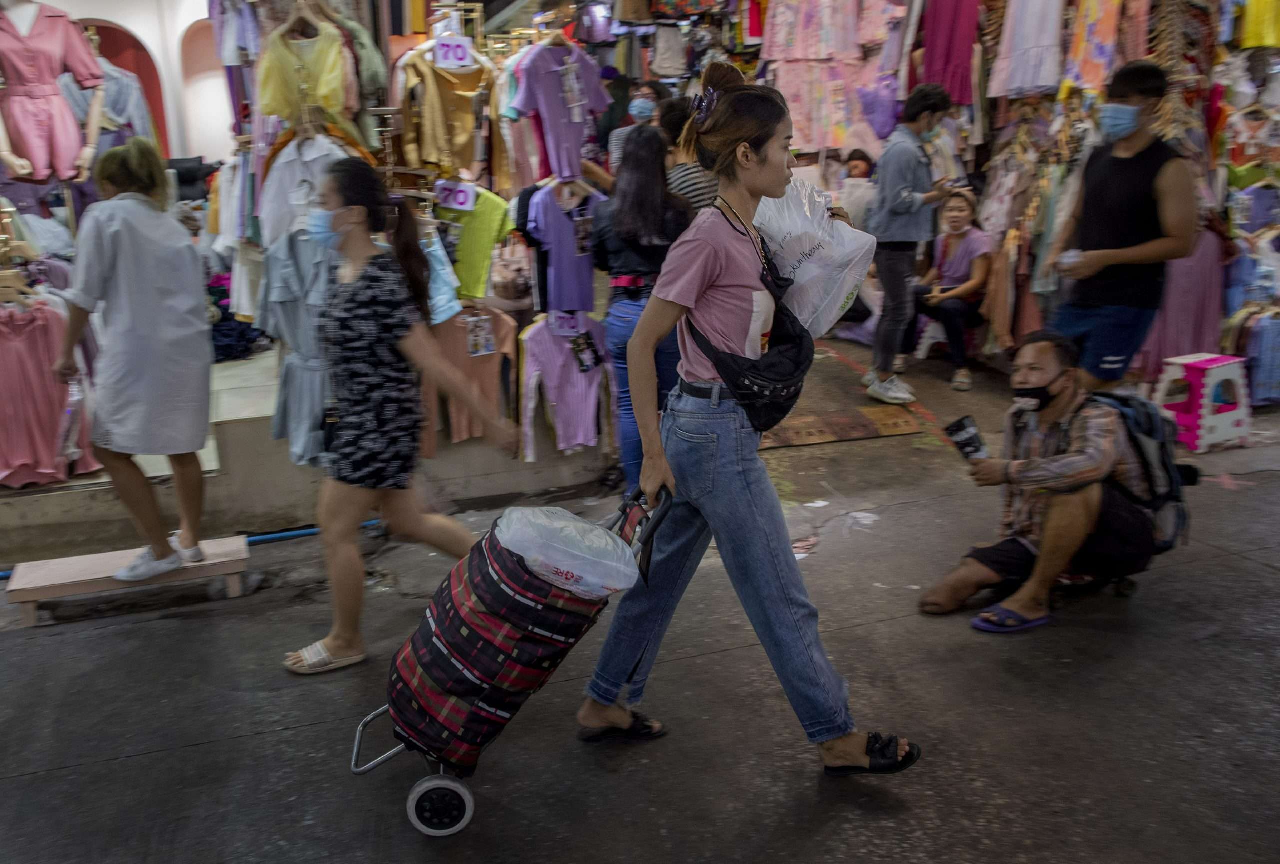 A shopper pulls a cart of clothing at a market in Bangkok, Thailand, one of the small tokens of technology eradicating global poverty.