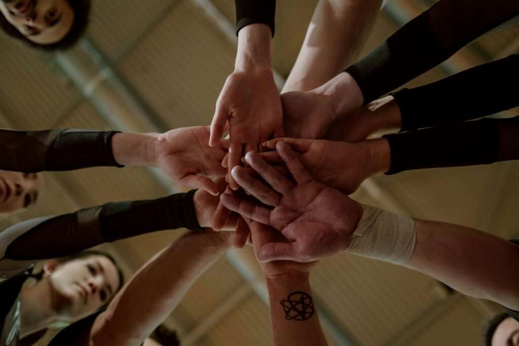 Diverse hands joined in a huddle showing unity and social support.
